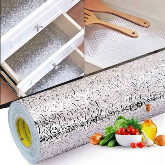 Roll of textured aluminum foil with kitchen setup and vegetables in the background